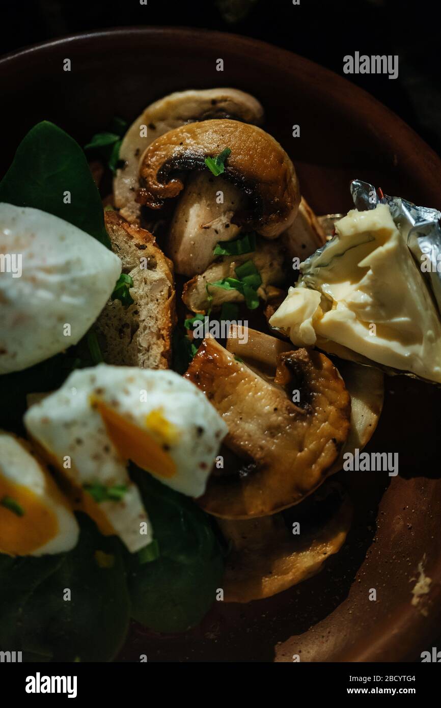 Appetizing breakfast boiled egg, toast, cheese and mushrooms in a clay plate on a wooden background. medium cooked egg. Stock Photo