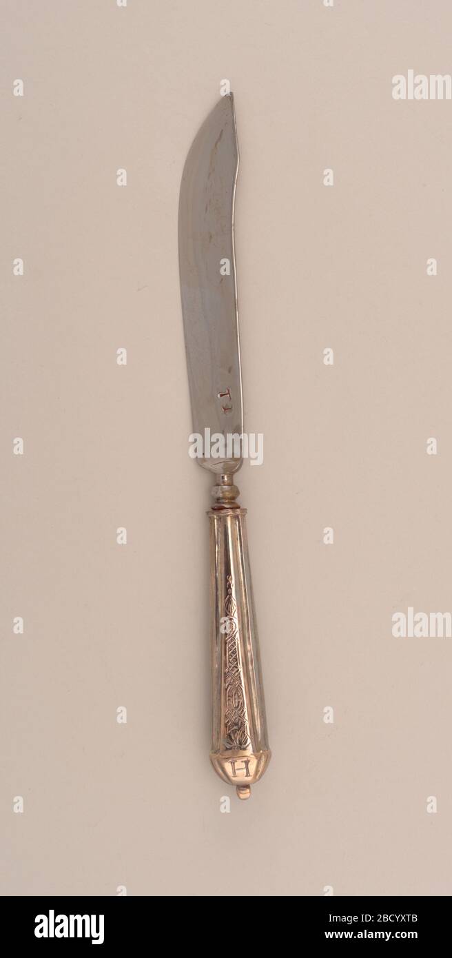 Knife. Research in ProgressSaber-shaped blade with concave bolster. Tapered silver handle with segmented panels to form rectangular profile. Front and back panels chased with decorative pattern fluted end with raised knop. Handle engraved at end with 'A' (converse) and 'H' (reverse). Knife Stock Photo