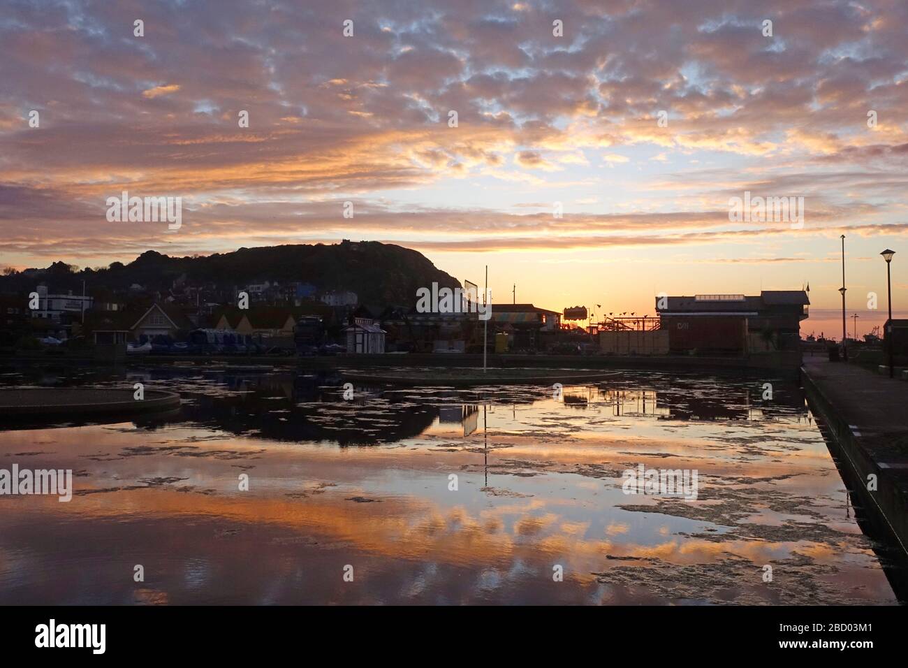 Hastings, East Sussex, 6th April 2020. Sunrise behind the Life Boat House from across the deserted boating lake. Very few people out this morning. Mild with clear skies turning cloudy and with light rain forecast for later. Carolyn Clarke/Alamy Live News Stock Photo