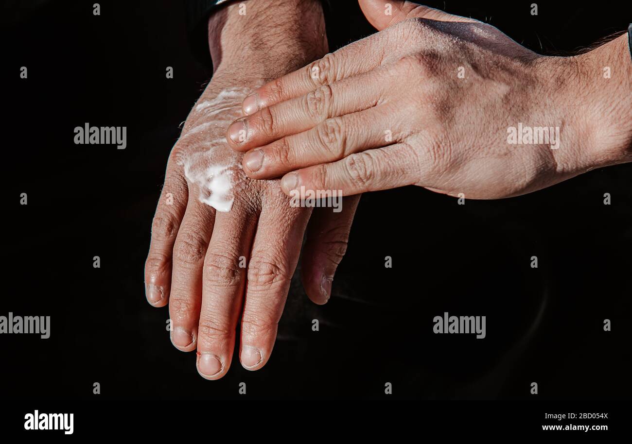man creams his rough hands after using disinfectant lotion Stock Photo