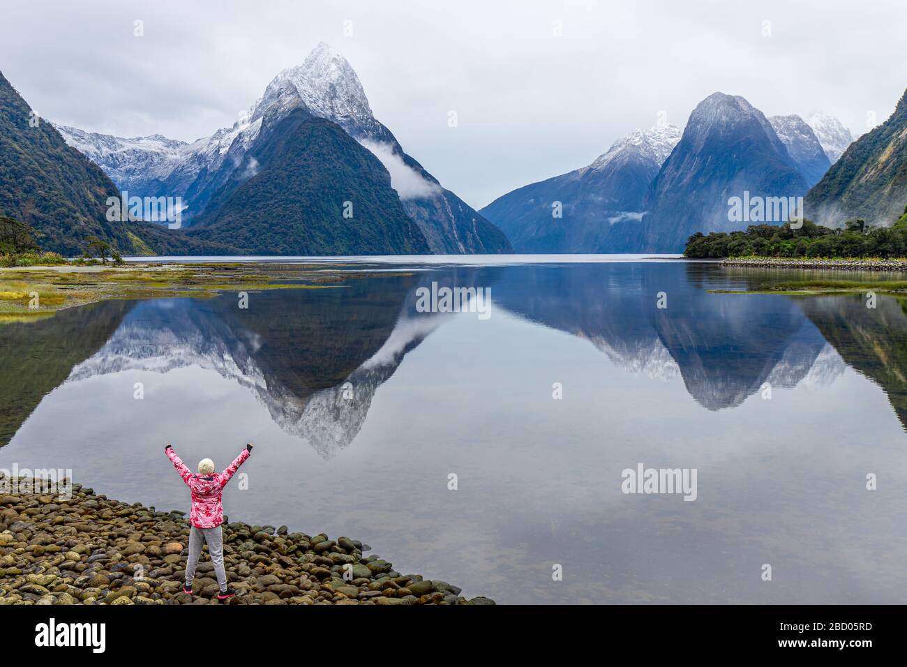 Young Asian traveler celebrating success at Milford Sound, Fiordland National Park, South Island, New Zealand Stock Photo