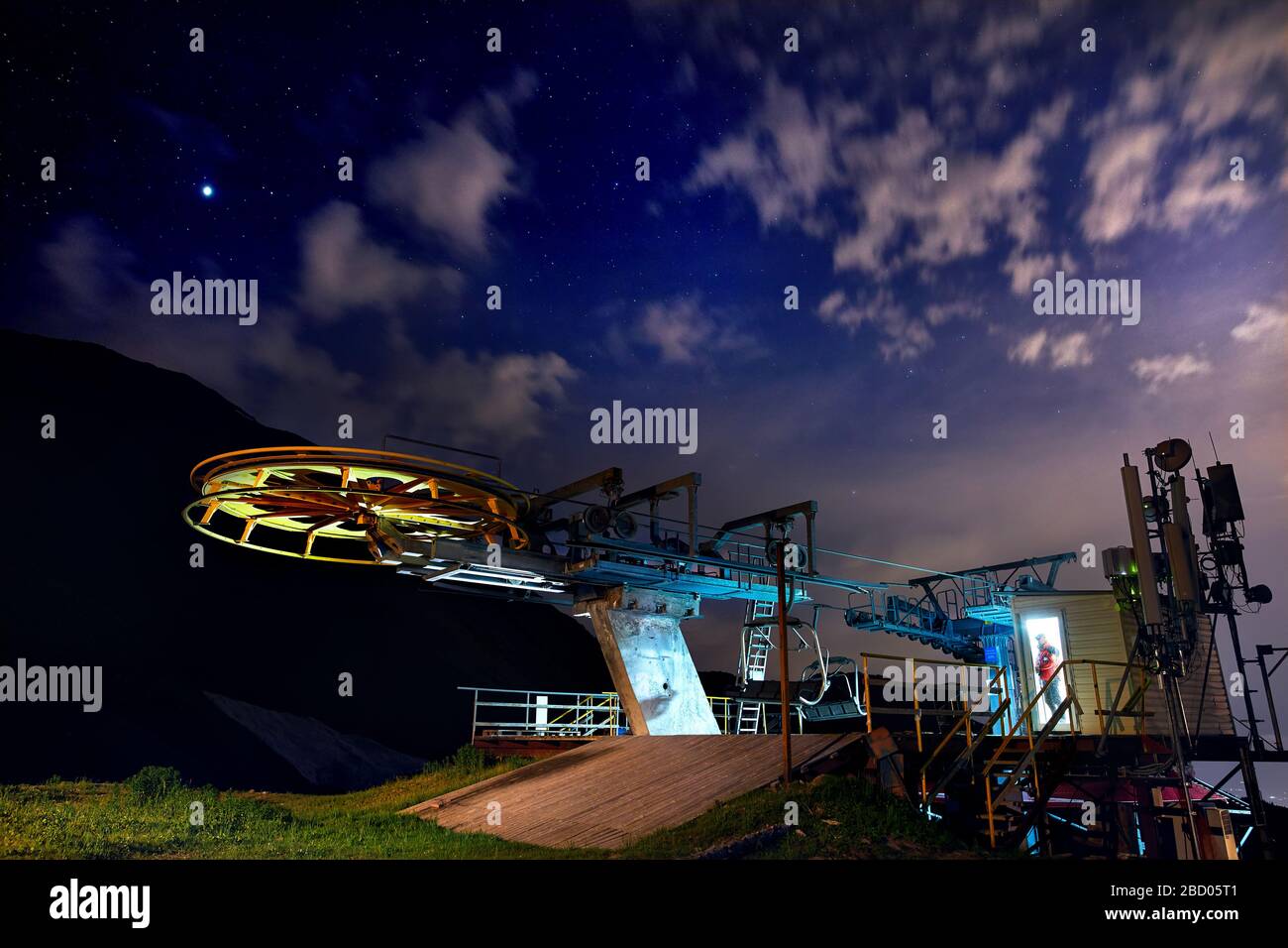 Cable car station with Lifeguard in red jacket in the door of building at the mountain ski resort with starry night sky Stock Photo