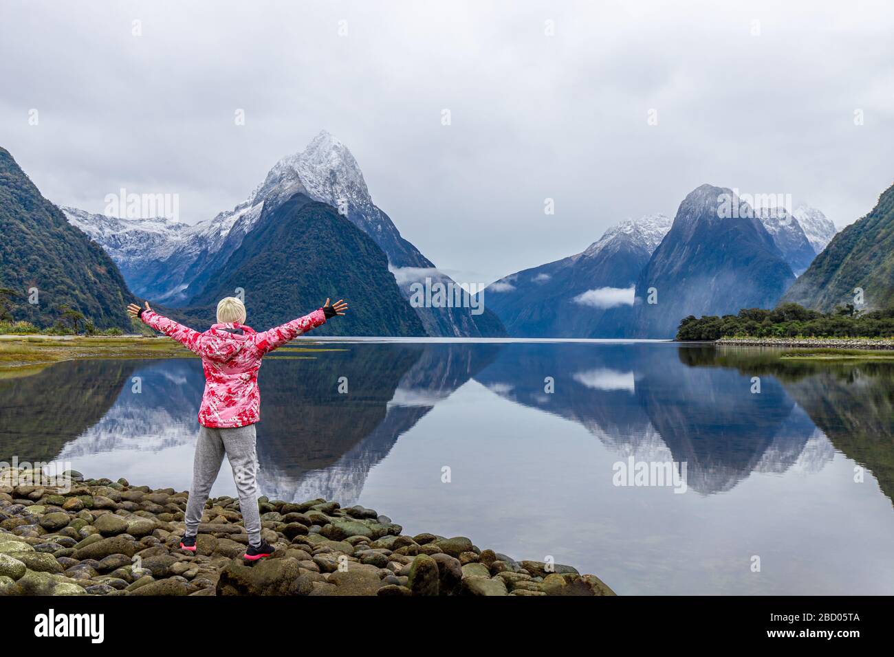 Young Asian traveler celebrating success at Milford Sound, Fiordland National Park, South Island, New Zealand Stock Photo