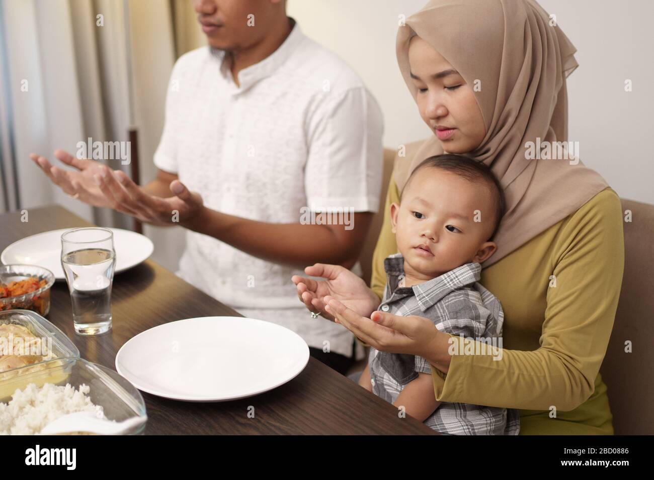 muslim family pray before having dinner together on ramadan Stock Photo