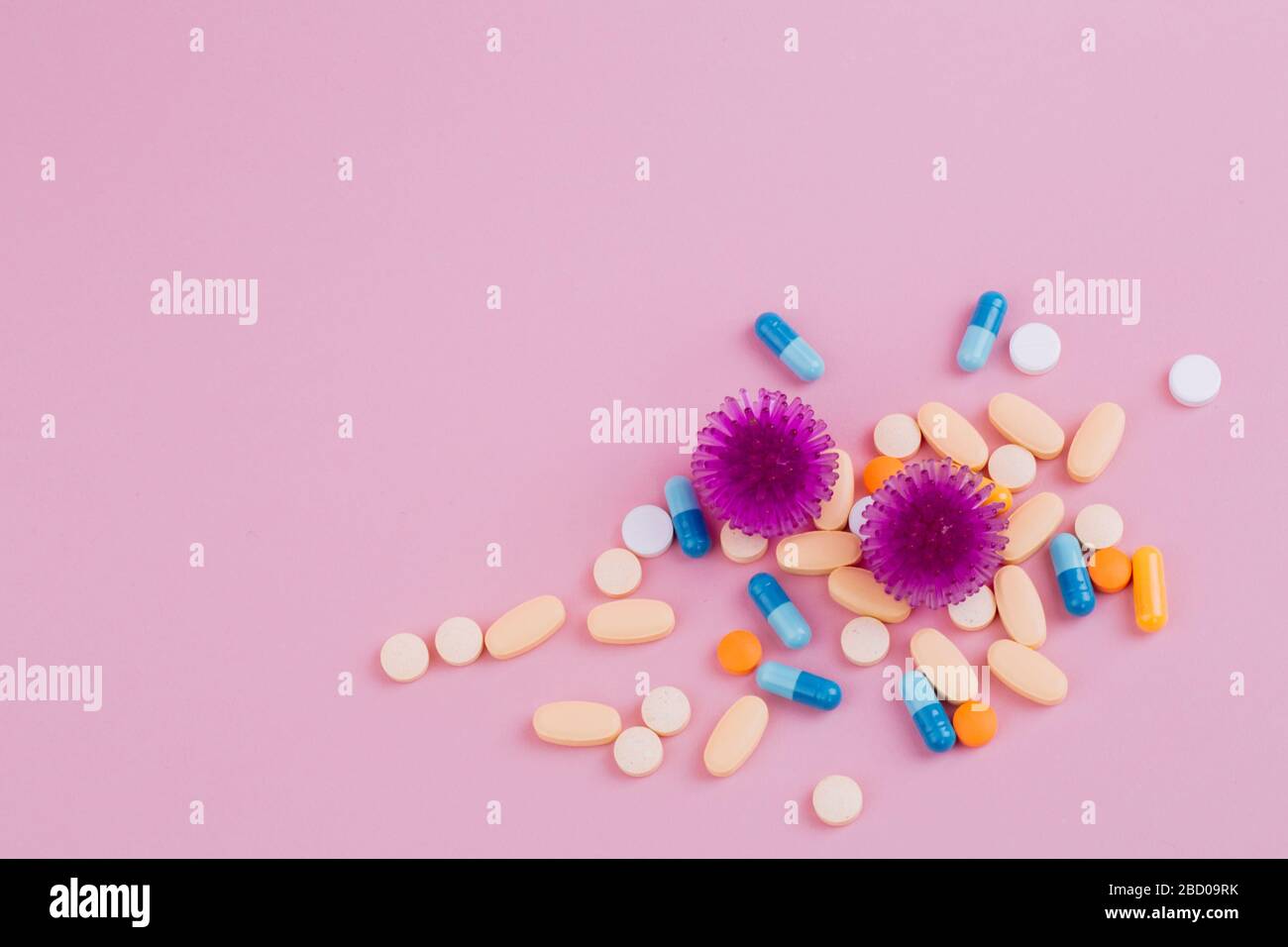 Abstract model of coronavirus infection of the strain Coronavirus. Violet virus and a diverse pill on a pink background, the risk of a pandemic. Copy space. Stock Photo