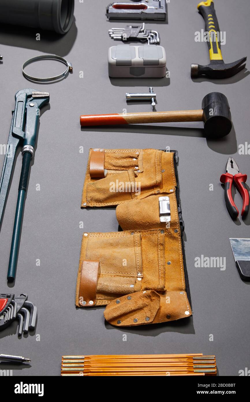 high angle view of tool belt, hammers, monkey wrench, putty knife, pliers,  calipers, rivet gun, angle keys and stapler on grey background Stock Photo  - Alamy