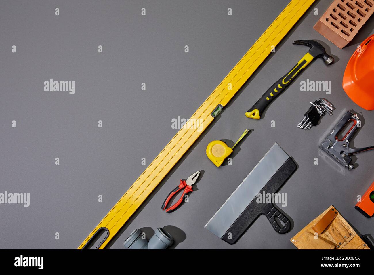 flat lay with brick, hammer, measuring tape, helmet, tool belt and industrial tools on grey background Stock Photo