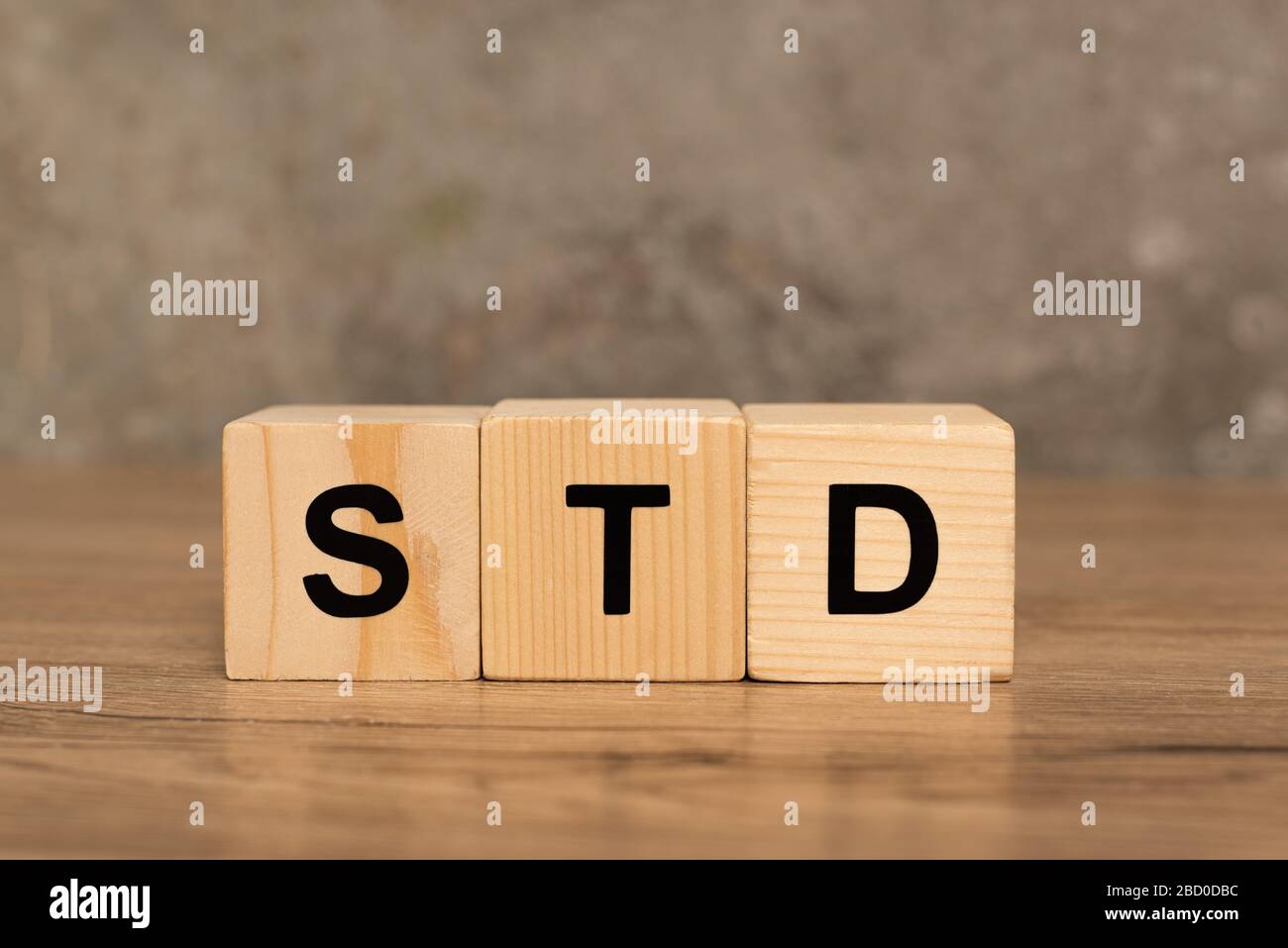 Wooden blocks with std letters on wooden table on grey background Stock Photo