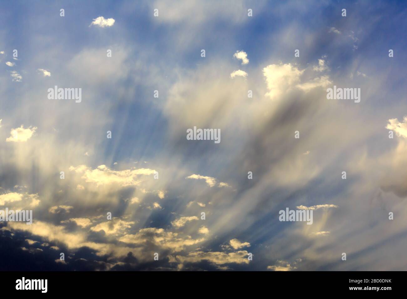 Evening sun rays streaming through clouds Stock Photo