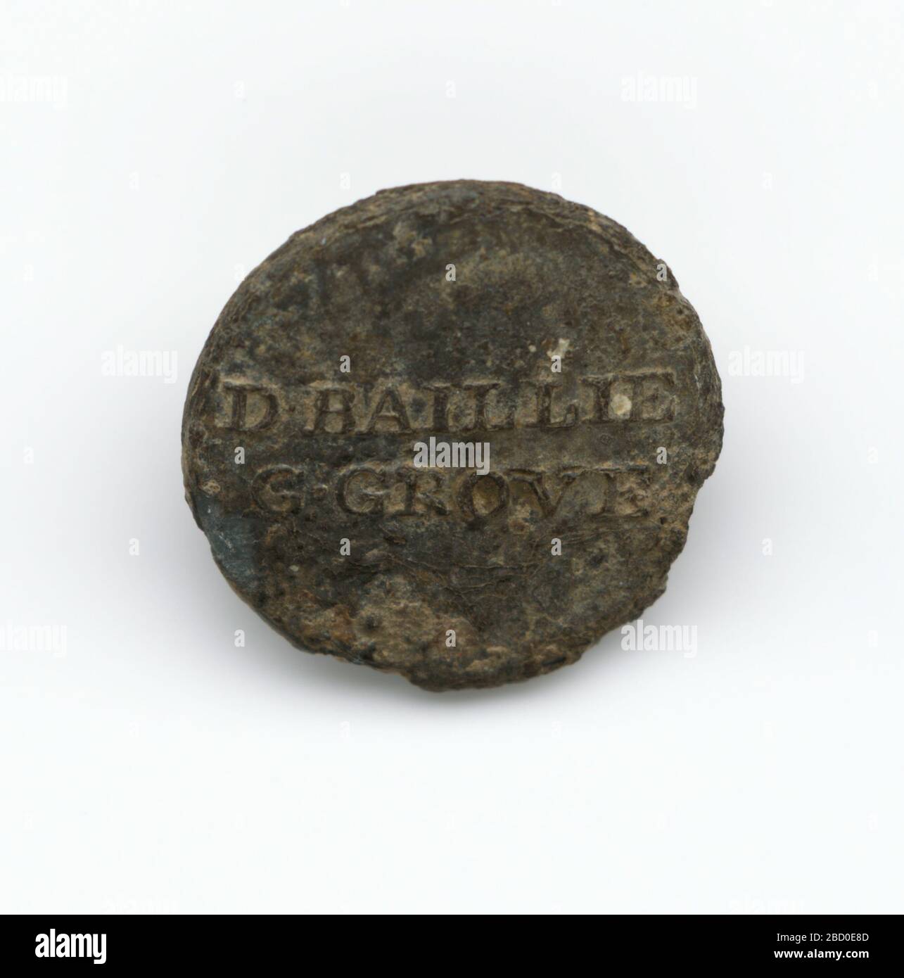 Identification button worn by enslaved persons on Golden Grove Plantation. A round pewter button with 'D BAILLIE / G•GROVE' stamped on the front. This button would have been sewn onto an enslaved person's shirt to identify him or her as belonging to David Baillie of Golden Grove Plantation, British Guyana. Identification button worn by enslaved persons on Golden Grove Plantation Stock Photo