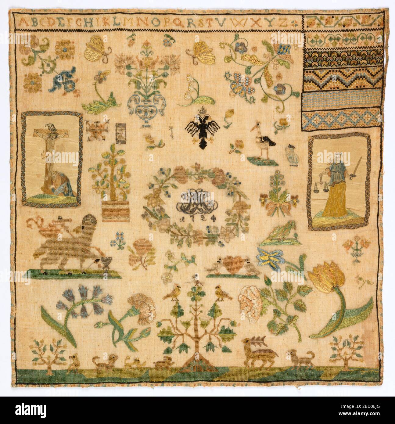 Sampler. Research in ProgressAlphabet at top. Box of pattern at upper right. Field filled with floral motifs. At left, applique of a silk picture of Christ on the cross. At right, applique of a silk picture of Justice. Sampler Stock Photo