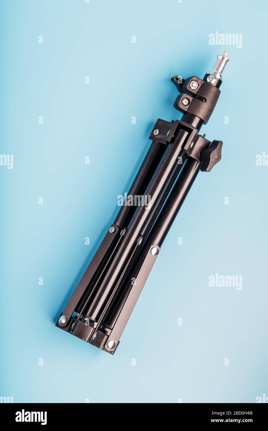 Folded Tripod on a blue background for a photo-video camera and flash ...