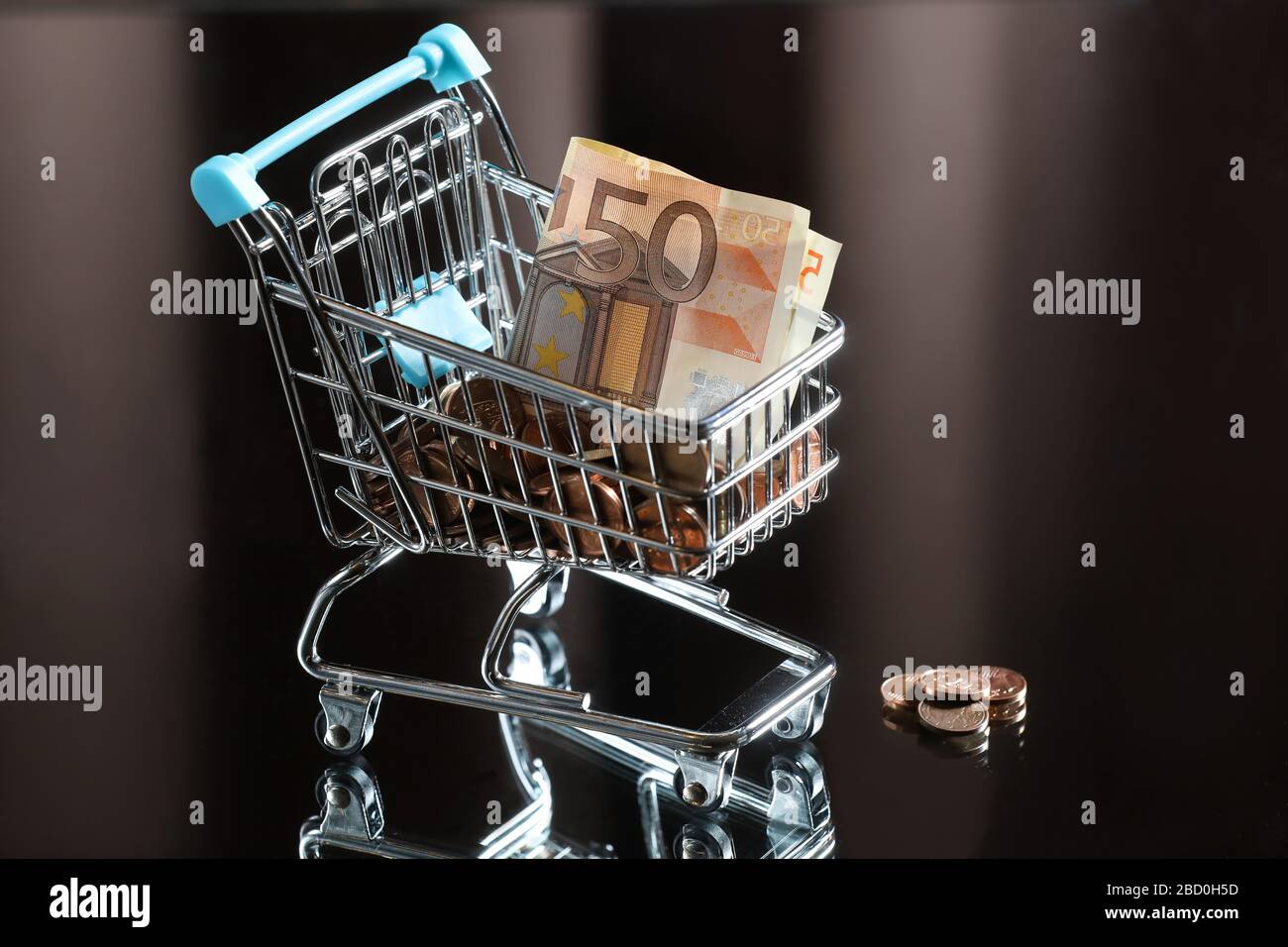 blue shopping cart with money. Reflected table. Dark background