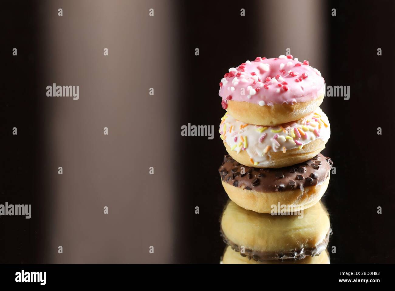 Three different donuts with reflection on a light and dark background. Stock Photo