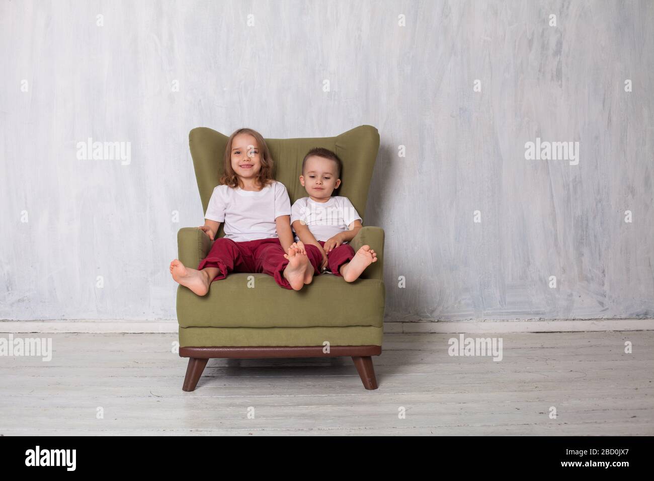 Boy and girl sit in vintage green chair Stock Photo - Alamy