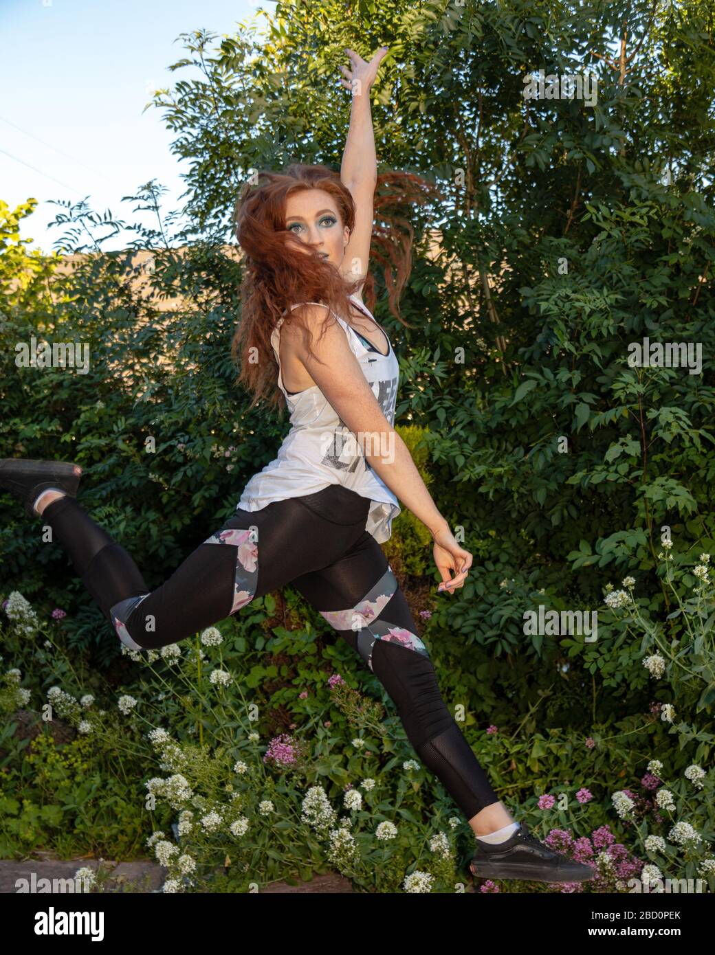 Young active female keep fit instructor jumping in the air outdoors, Caerphilly, South Wales, UK Stock Photo