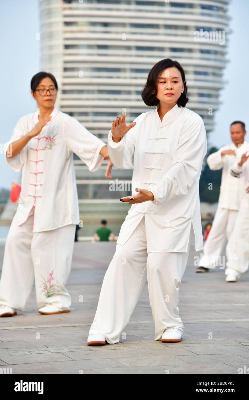 Huzhou, China, October 2019; Large group of people practicing Tai Chi, Yang style in early evening on the shore of Tai Lake Stock Photo