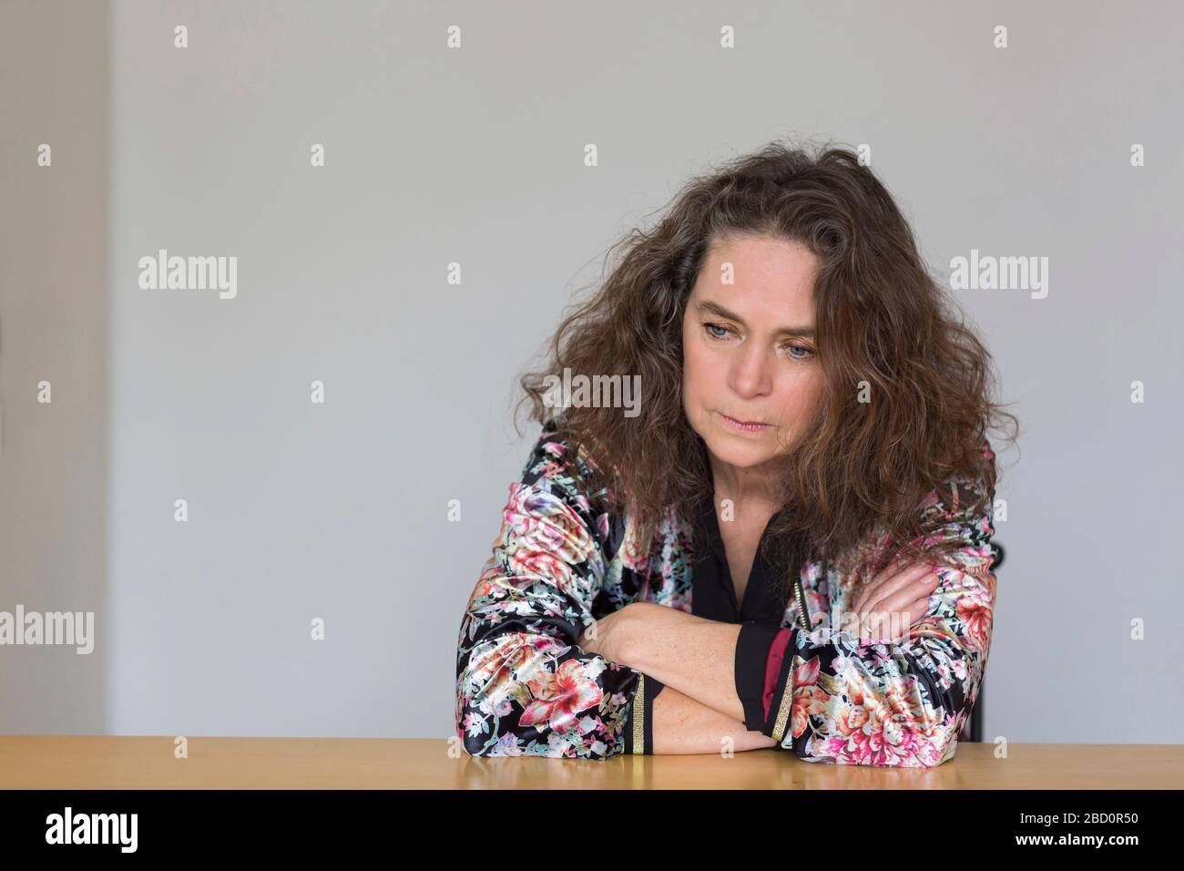 Portrait of worried mature woman sitting at table Stock Photo