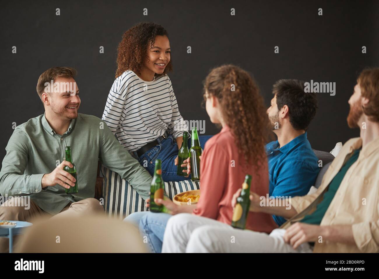 Large group of friends enjoying beer and snacks during home party ...