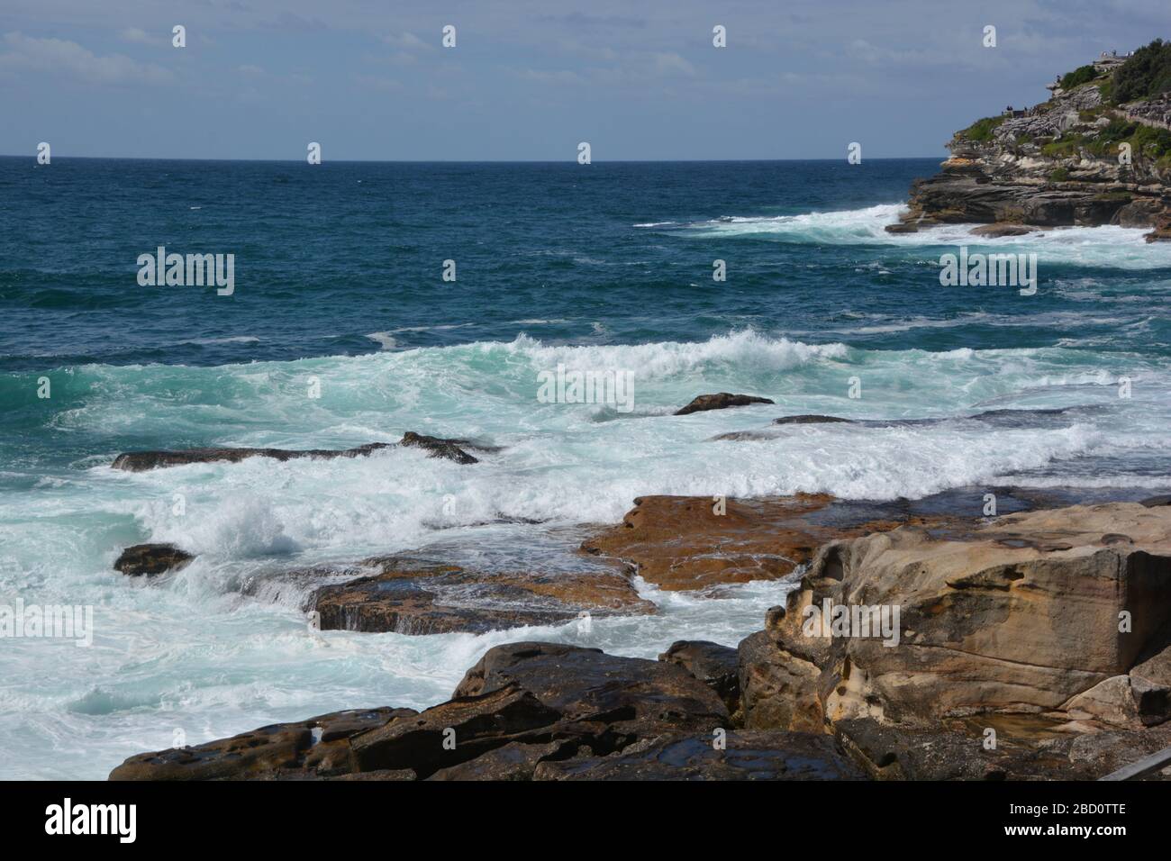 High angle ocean view overlooking the rock formations with crashing waves at Bondi; visible the Bondi to Bronte coastal walk Stock Photo