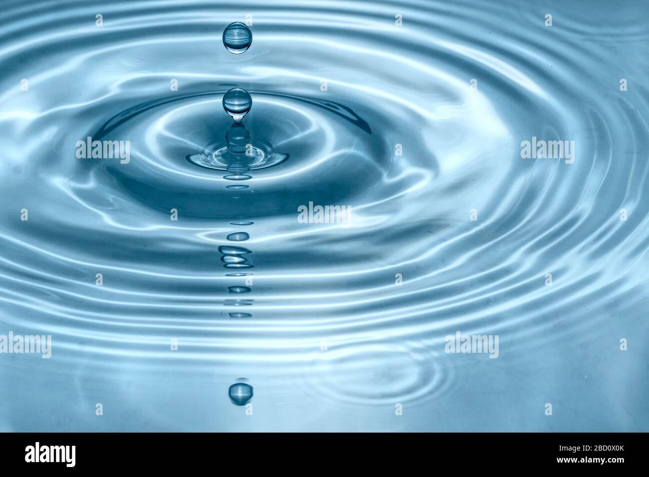 Water drops splash in a glass blue colored Stock Photo