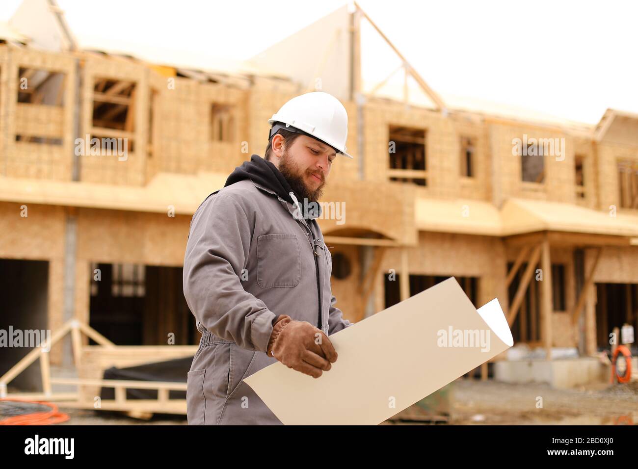 Foreman holding architecture drawing plan on paper at construction site. Stock Photo