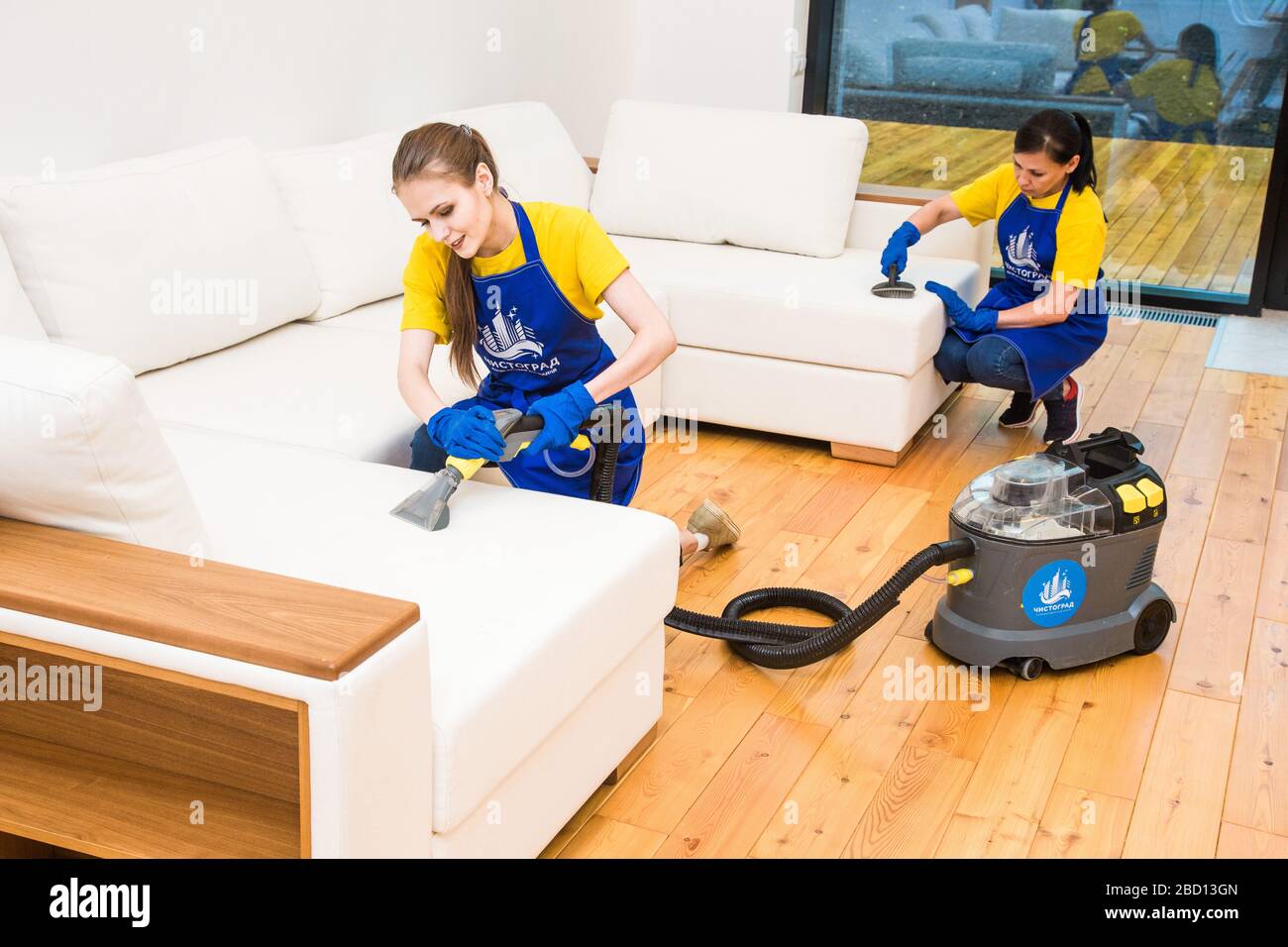 professional cleaning service. Two women in working uniform, in aprons ...
