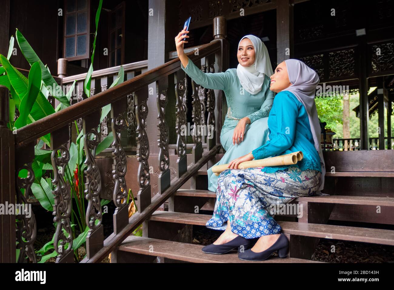 Muslim Malay Women Wearing Hijab And Traditional Costume Are Taking Selfie During Aidilfitri Celebrations At The Terrace Of Traditional Wooden House Stock Photo Alamy