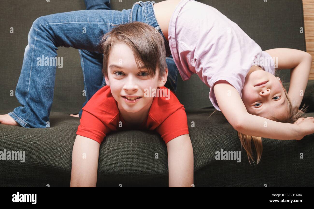 Siblings climbing the walls going mad stuck at home being in self-isolation. Quarantine and lockdown protective measures against spreading of coronavi Stock Photo