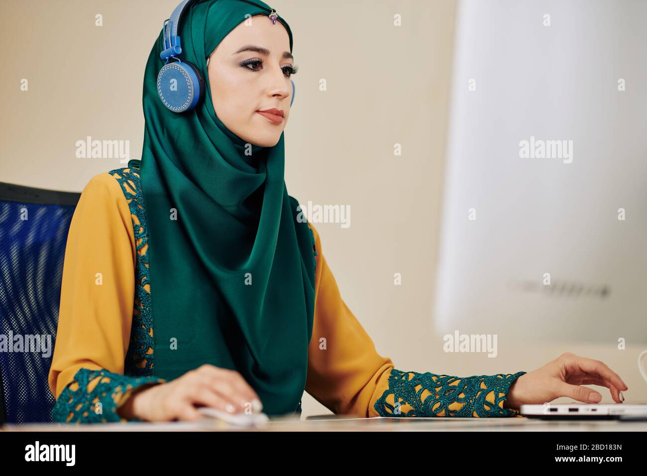 Young serious muslim woman in hijab listening to music in headphones ...