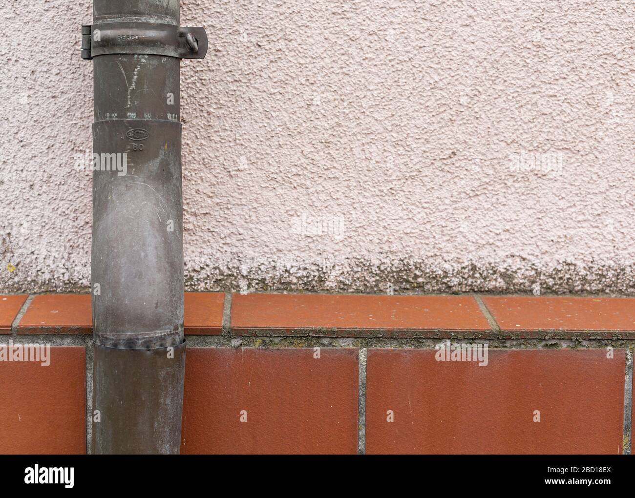 Rainwater drainage pipe. Sewage system. Pipes on the facade of the building. House after renovation. Metal constructions. Rough surfaces. Stock Photo