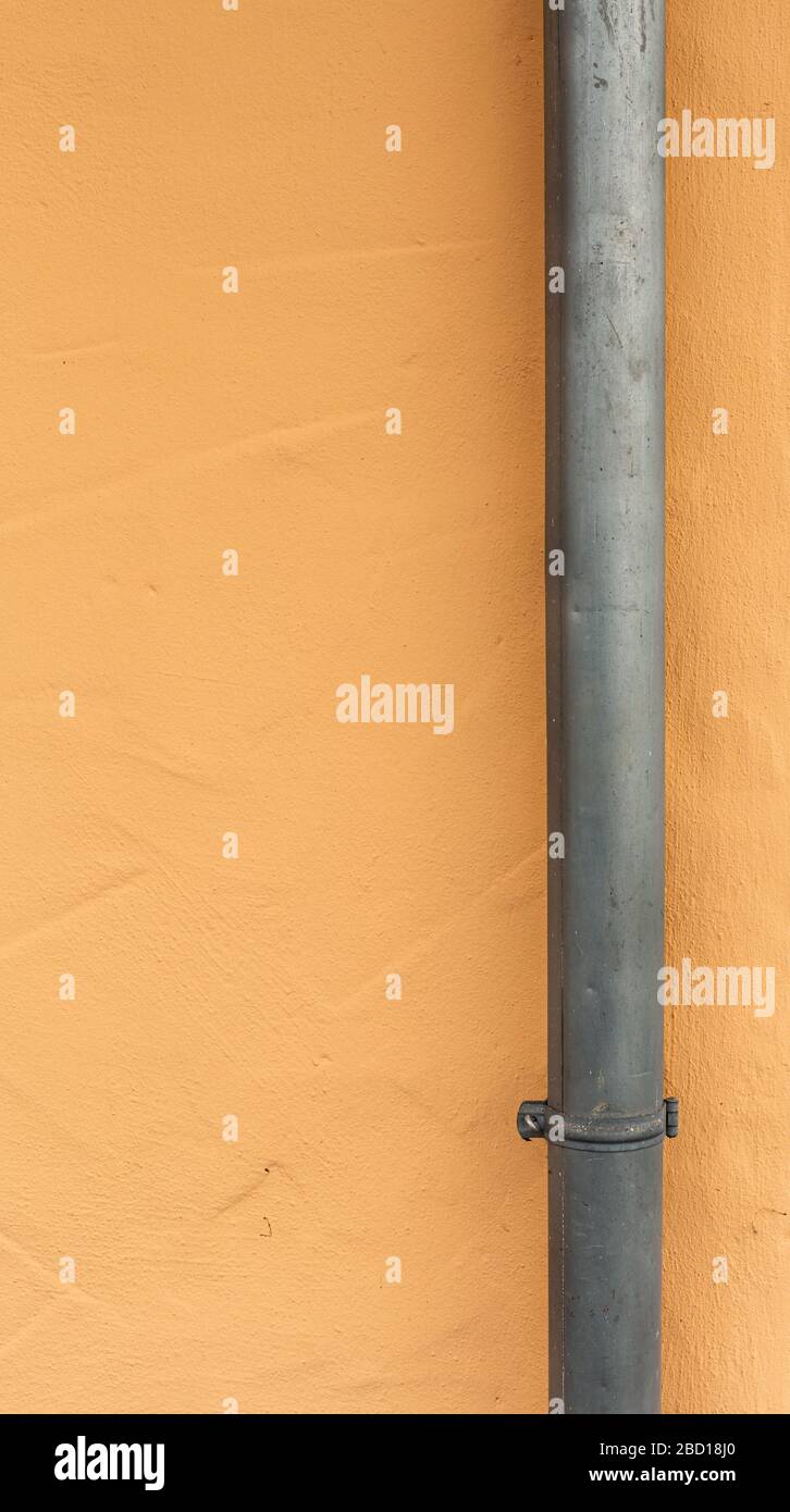 Rainwater drainage pipe. Sewage system. Pipes on the facade of the building. House after renovation. Metal constructions. Rough surfaces. Stock Photo
