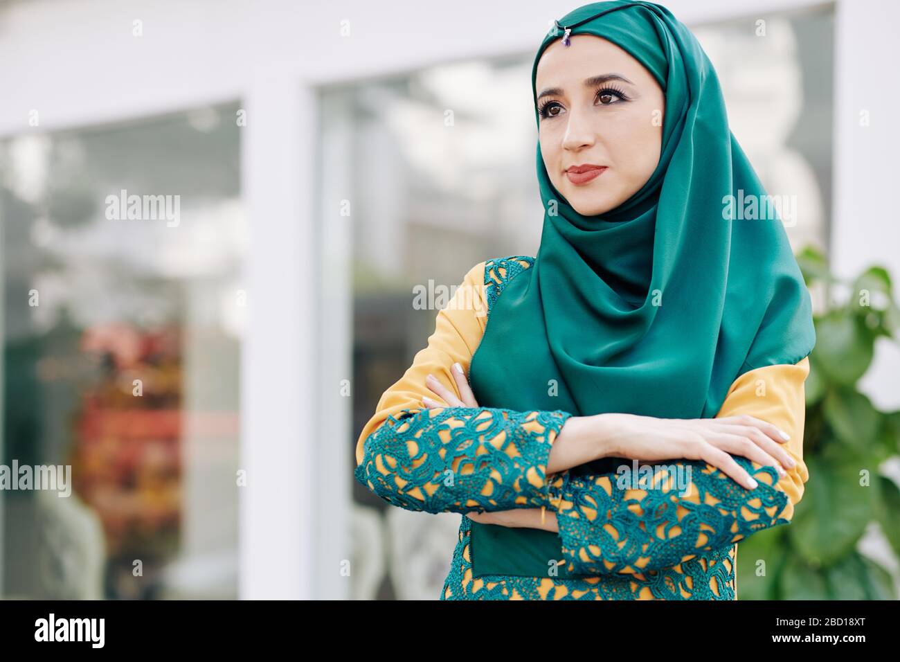 Confident determined young muslim woman in hijab folding arms and looking in front of her Stock Photo