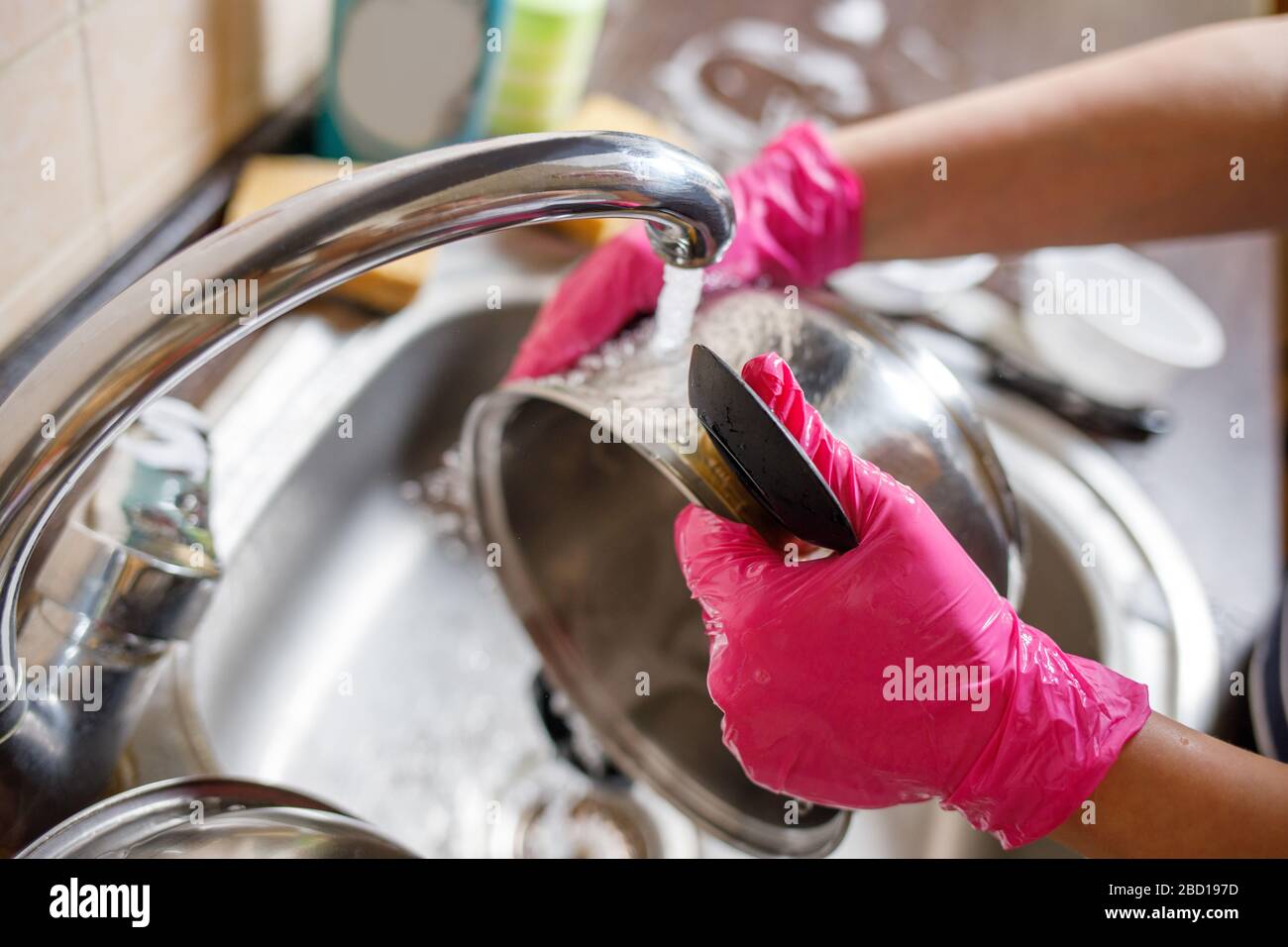 Woman in rubber gloves washing up dishes and pot. Stay home clean house ...