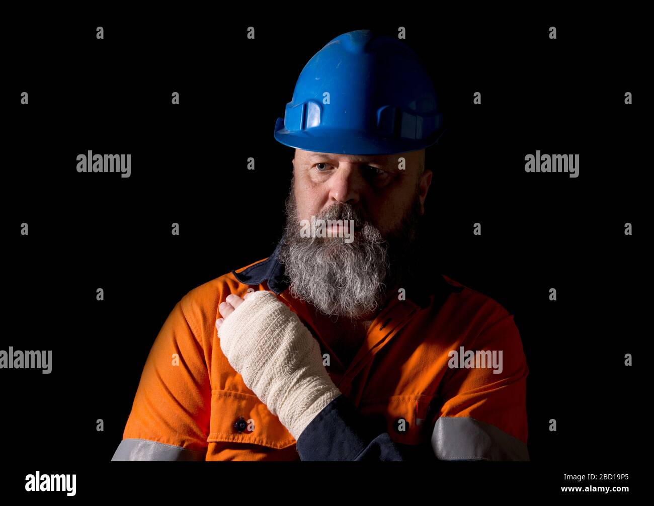 A male worker with a hand injury, on a black background with copy space. Stock Photo