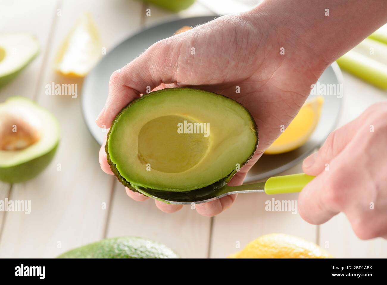 Man preparing avocado, scooping its flesh out with a spoon Stock Photo
