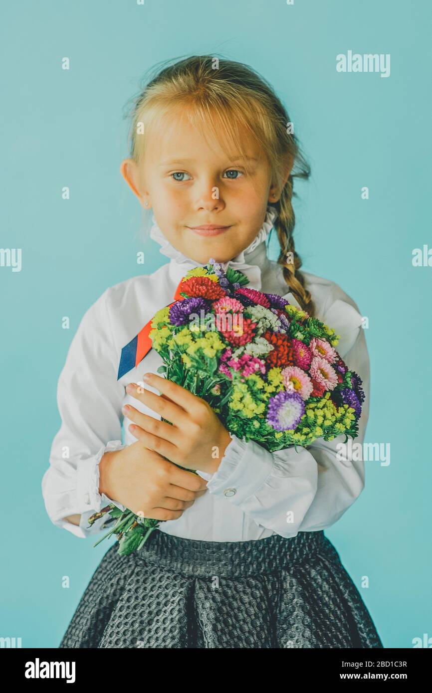 Adorable six years old girl in white tshirt isolated on blue studio background, pretty european