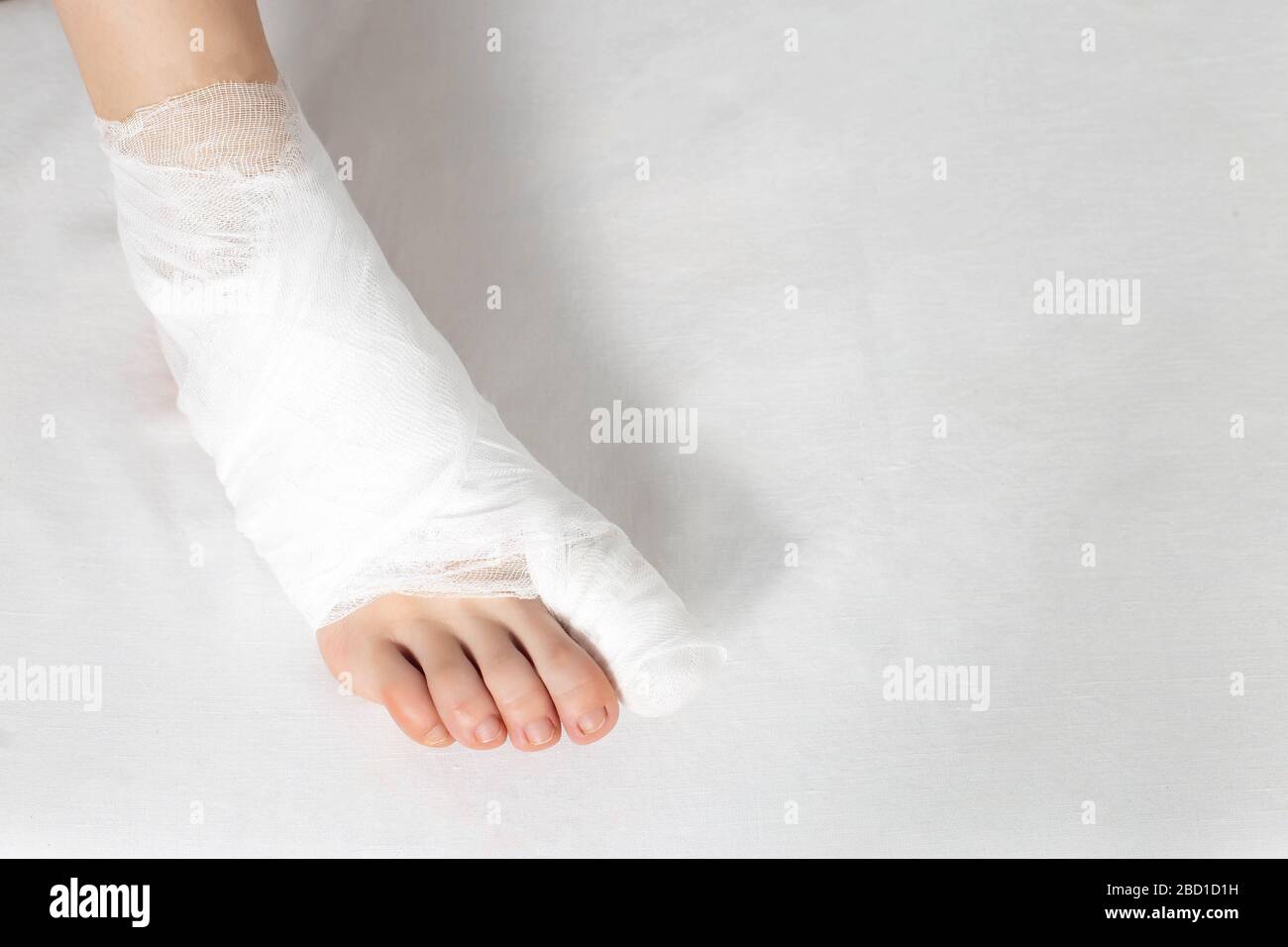 Bandaged big toe with foot on white background. Concept of fracture of