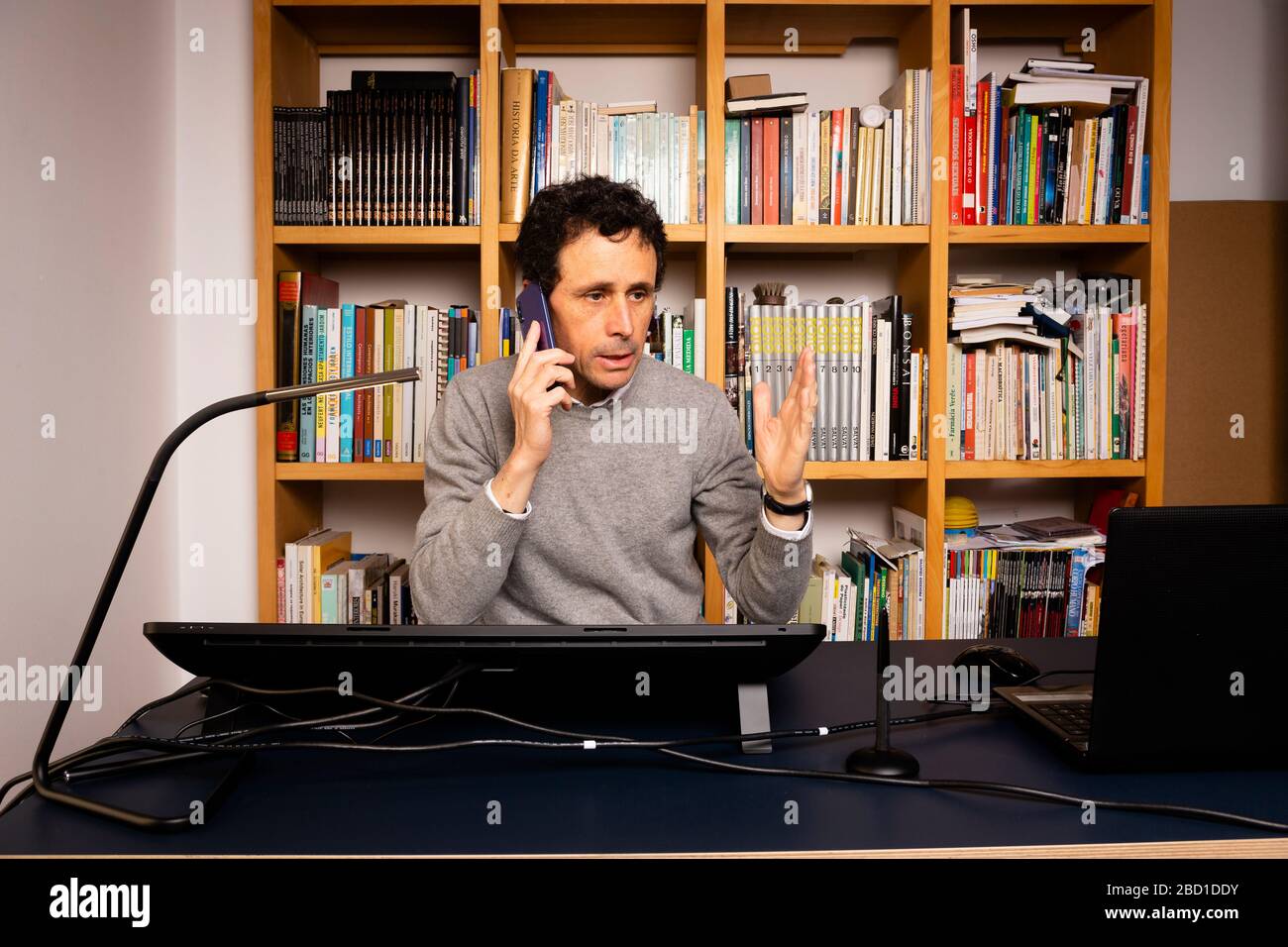 Photographer, wearing a white shirt and glasses, editing photos on a graphics tablet at home. Stock Photo
