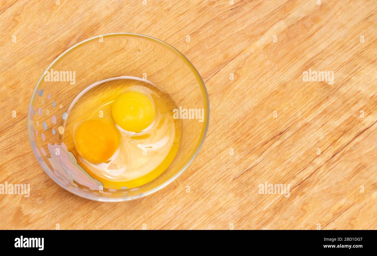 Two chicken eggs, homemade and factory, are broken in a glass plate. Difference concept of homemade natural eggs from store-bought, organic Stock Photo