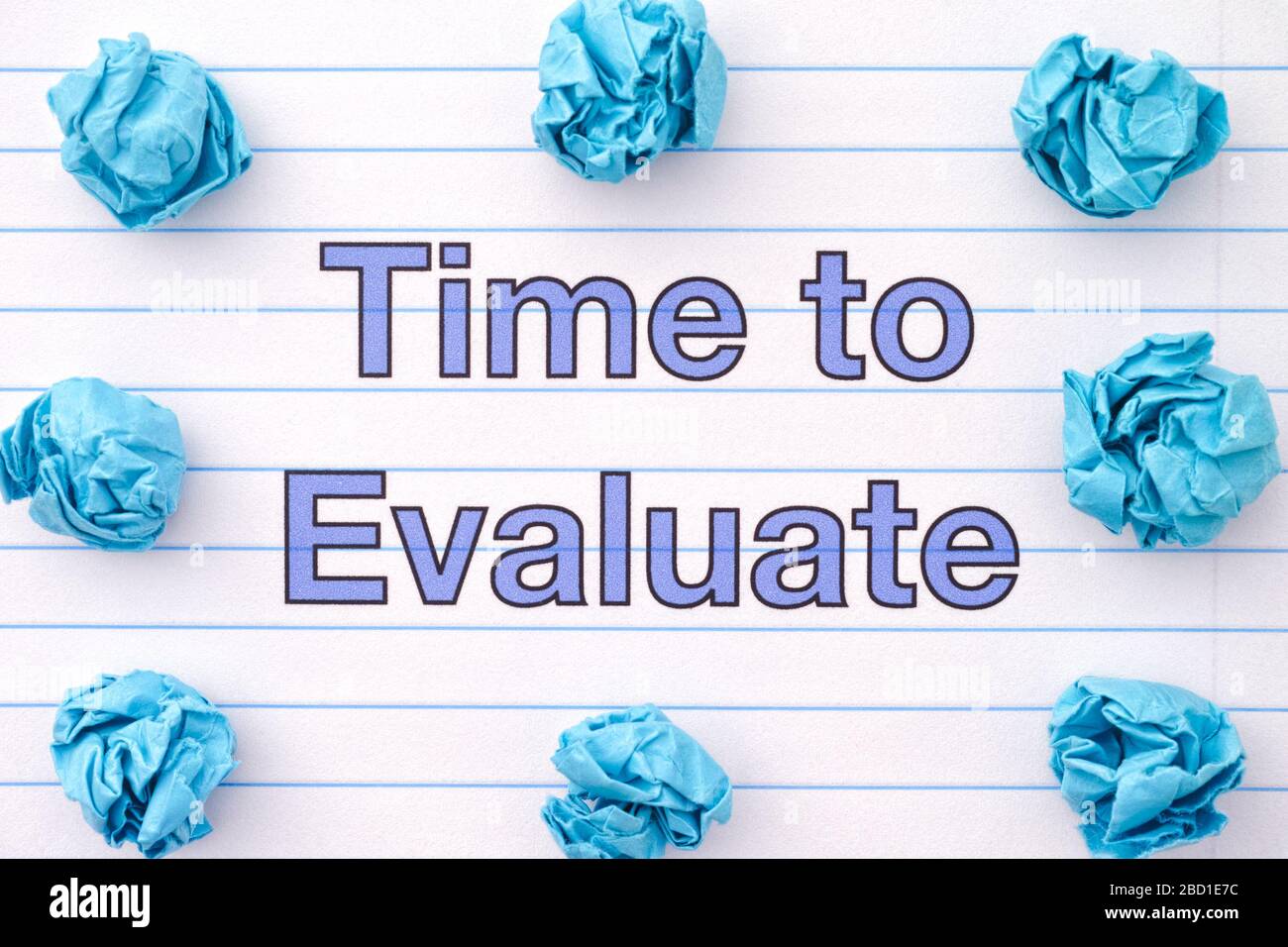 The phrase Time To Evaluate written on a lined notebook sheet with some crumpled paper balls around it. Close up. Stock Photo