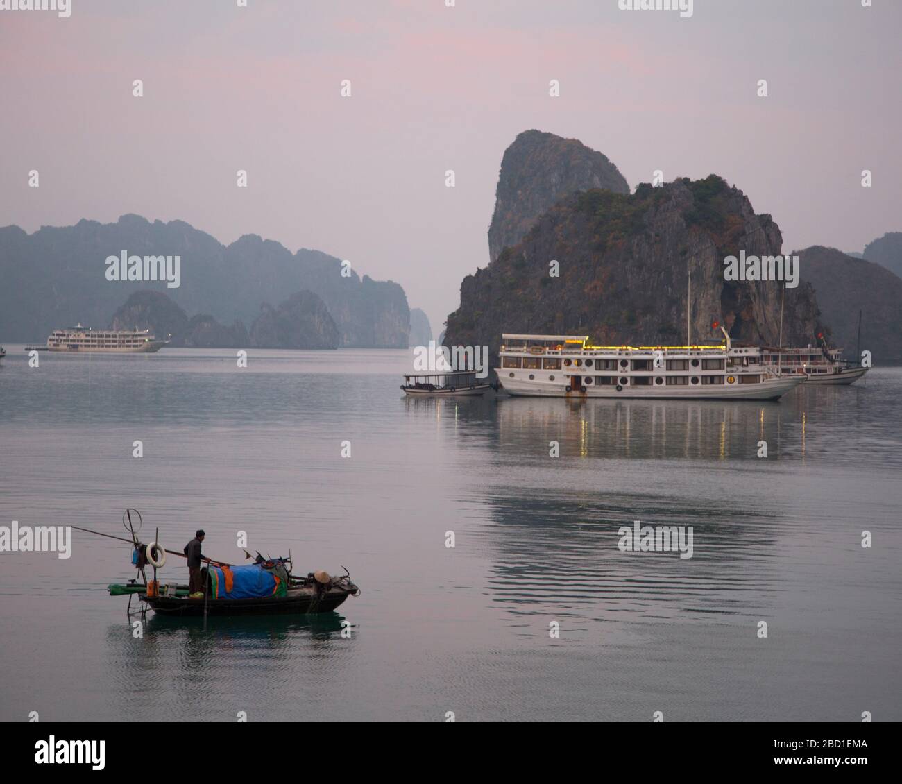 An Early morning view of Ha Long Bay with local fishing boats and Tour Boats among the Limestone cliff formations, Stock Photo