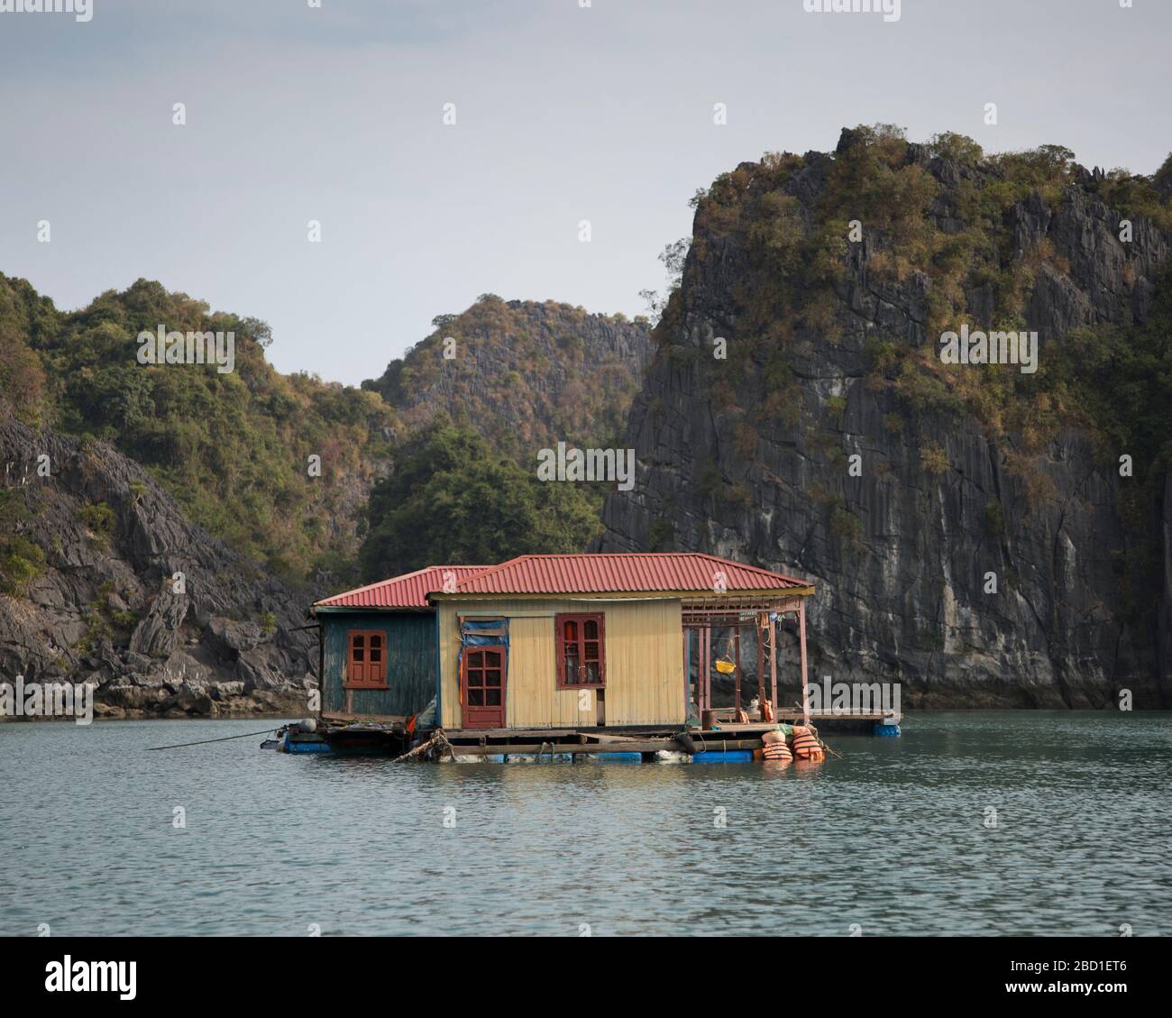 A floating house in the fishing villages of Ha Long Bay among the Limestone cliff formations, Stock Photo