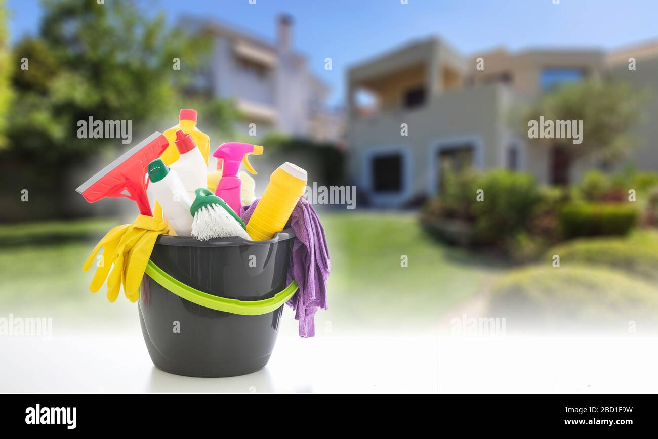 Cleaning products against blur house facade background. Chemical detergents in a bucket, spring home household concept, copy space Stock Photo
