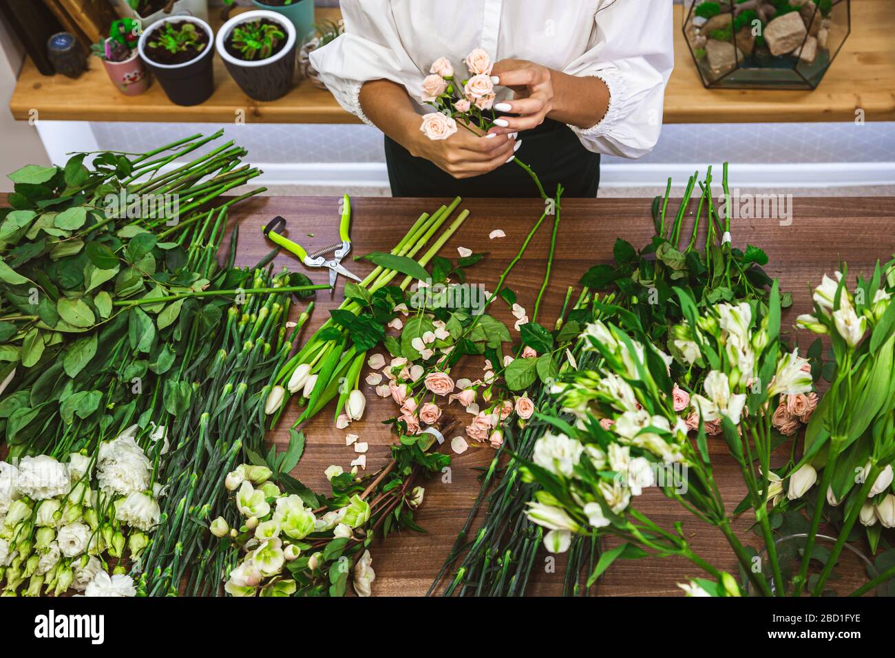 Attractive young woman florist is working in a flower shop Stock Photo ...