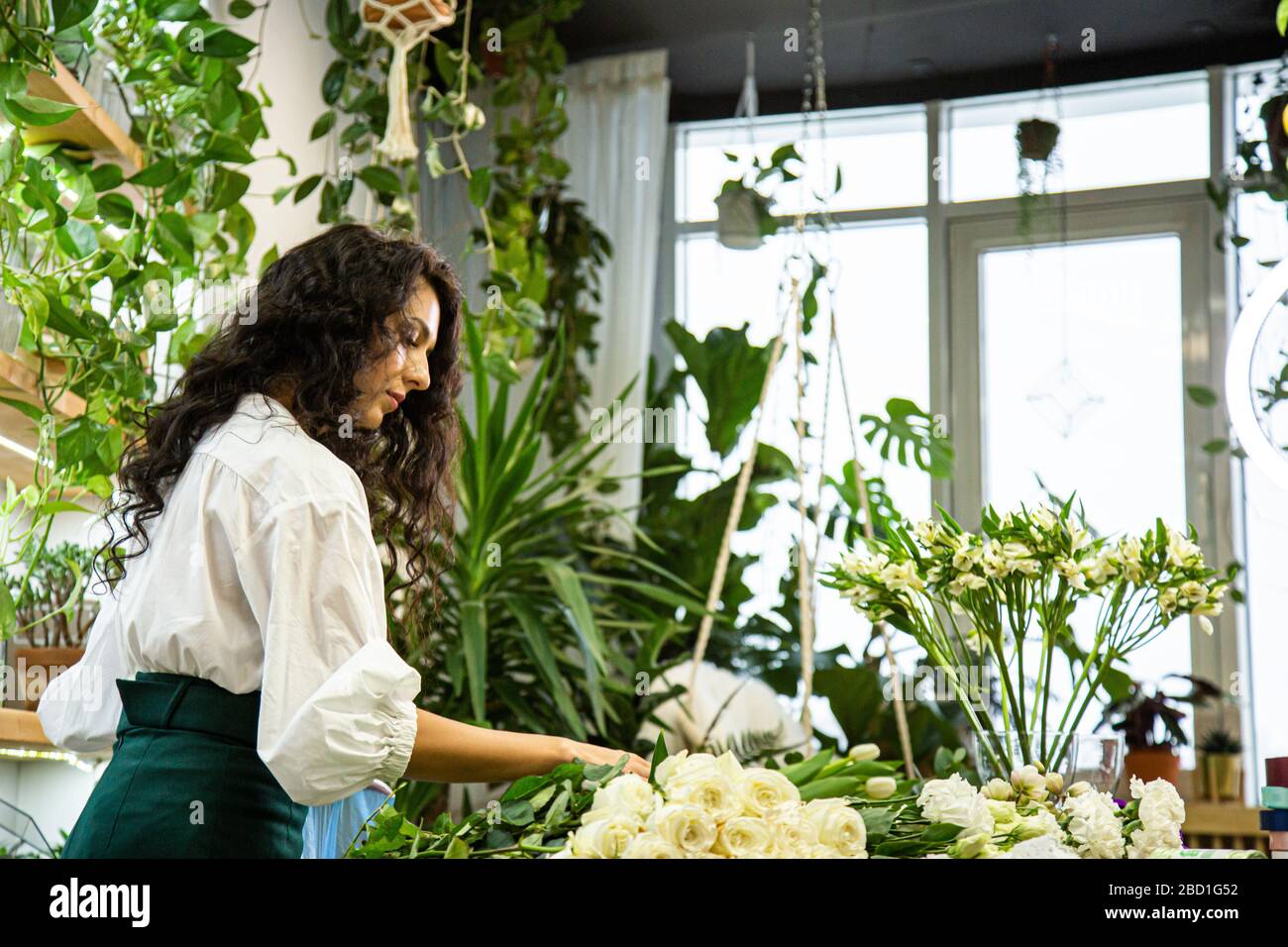 Attractive young woman florist is working in a flower shop Stock Photo ...