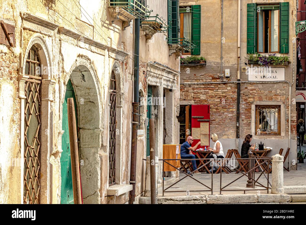 People eating outside a small family run restaurant, Al Ponte Storto Osteria near Ponte Storto canal bridge in a quiet back street of Venice Stock Photo