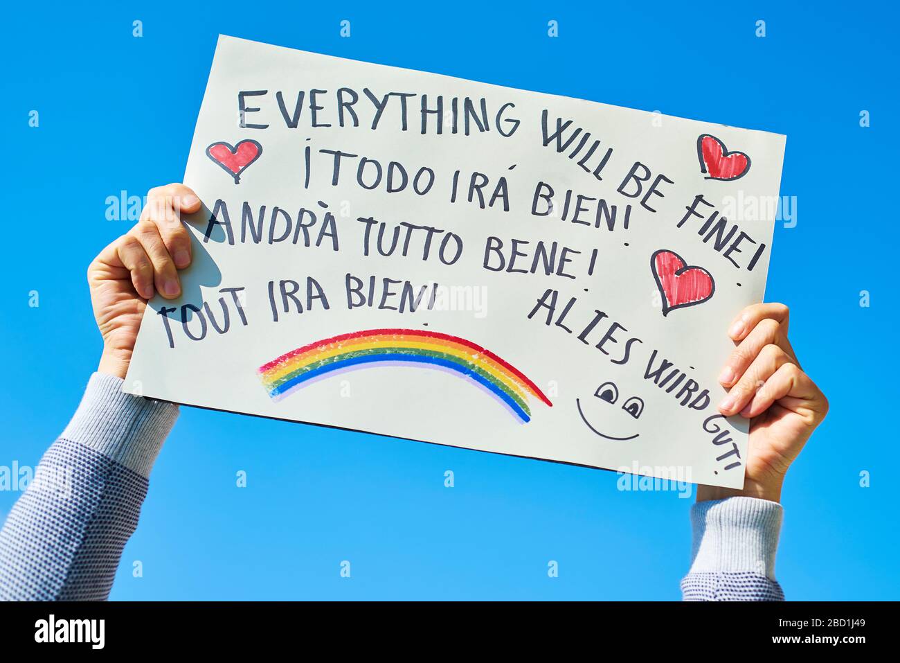 man showing a homemade sign with the text everything will be fine in different languages, such as Italian, German or French, as a message of hope duri Stock Photo