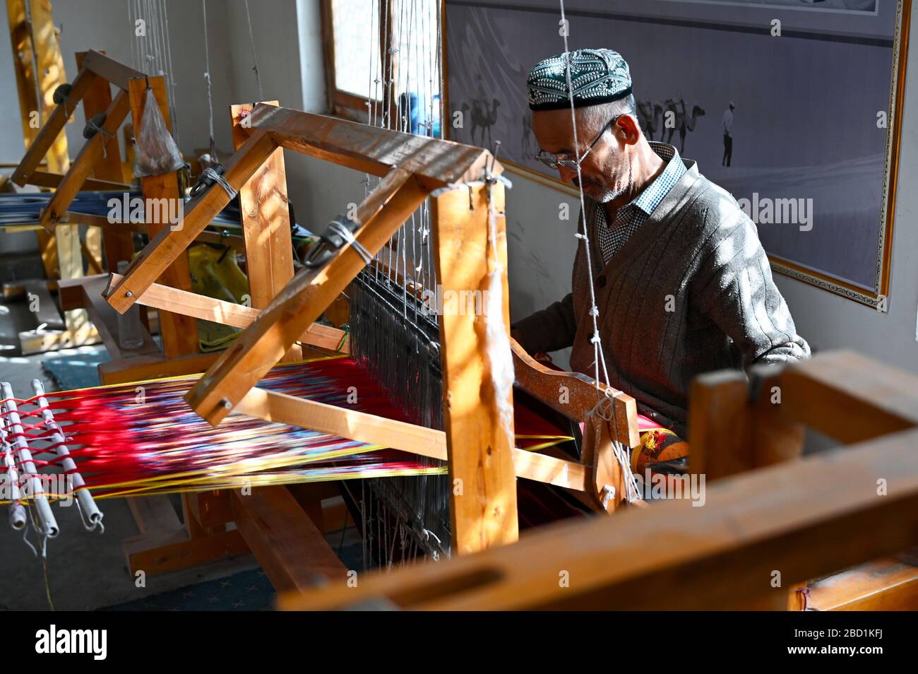 Uyghur man at loom weaving tie dyed silk thread into traditional cloth, Jiya, Xinjiang, China, Asia Stock Photo