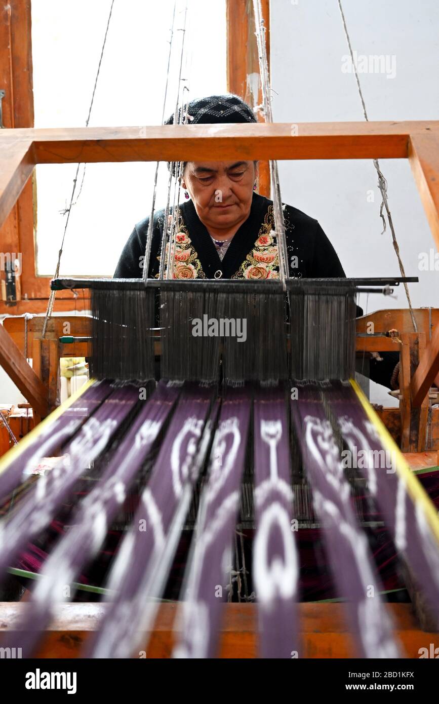 Uyghur woman at loom weaving tie dyed silk thread into traditional cloth, Jiya, Xinjiang, China, Asia Stock Photo